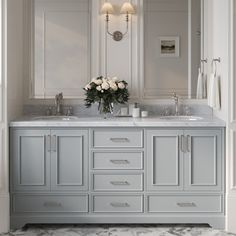 a bathroom with double sinks and marble counter tops in white walls, along with two mirrors