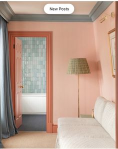 a bedroom with pink walls and white bedding in front of a door that leads to a bathroom