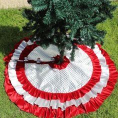 a christmas tree skirt sitting on the ground next to a small tree in a yard