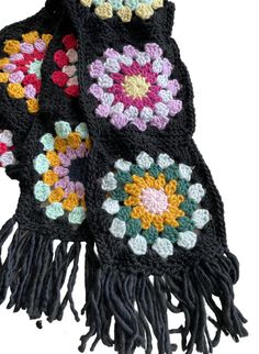 a black scarf with multicolored crocheted flowers on it and fringes