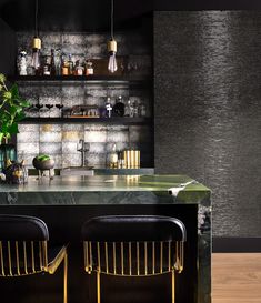 the bar has two stools and a green marble countertop with gold barstools