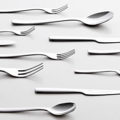 forks and spoons are arranged on a white surface