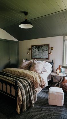 a bedroom with a bed, chair and ottoman next to a large painting on the wall