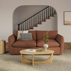 a living room filled with furniture and a stair case in the back ground near a coffee table