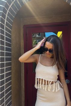 a woman standing in front of a red door with her hand on her head and wearing sunglasses