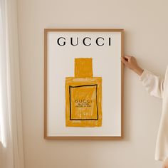 a woman standing in front of a gucci poster hanging on the side of a wall