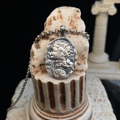 a coin is sitting on top of a marble pedestal with chains around it and an antique necklace hanging from the front