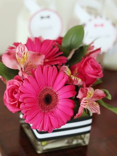 a vase filled with pink flowers on top of a wooden table