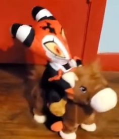 a stuffed animal is on the floor next to another stuffed animal that has an orange and black stripe