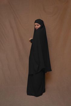 Introducing Black Moira Prayer Umrah Gown with Niqab Feature from Annah Hariri. This beautiful gown is made from high-quality Nada abaya fabric and features super light, stretchy jersey sleeves for ultimate comfort. The elasticated waistband and full skirt ensure a flattering and secure fit, while the khimar can be tied at the back of the head for added coverage.But the best part? This gown can also be transformed into a niqaab with just a few simple stitches. So whether you're performing Umrah, Abaya Fabric, Annah Hariri, Modest Activewear, Full Coverage Swimsuit, Back Of The Head, Abaya Dress, Niqab, Beautiful Gowns, Active Wear Tops