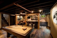 a pool table in the middle of a room with stairs and pictures on the wall