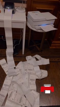 a pile of papers sitting on top of a wooden floor next to a computer desk