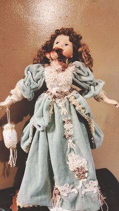 the doll is wearing a blue dress with white laces on it's arms