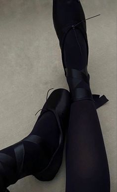 the legs and ankles of a woman in black tights, with her feet propped up