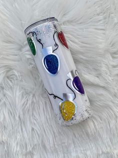 the tumbler is decorated with colorful hearts and balloons on it's side, sitting on a fluffy white surface