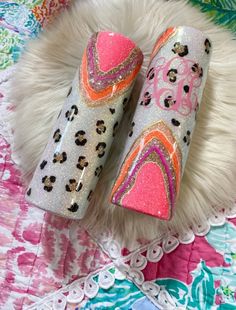 two pink and orange nail polishes sitting on top of a white fur covered rug