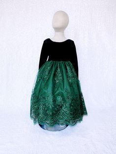 a mannequin wearing a green and black dress on a white background with snow