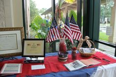 an american flag centerpiece is displayed on a red table cloth with other items around it