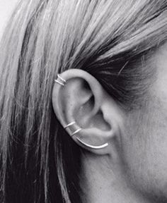 a close up of a person with ear piercings on their ears and behind them is a black and white photo