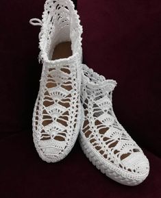 white crocheted slippers are sitting on a purple surface, with the soles covered in lace