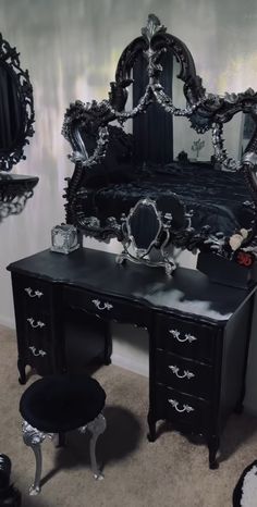 an ornate black vanity with mirror and stool