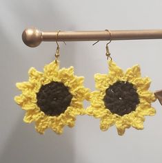 two crocheted sunflowers hanging from hooks