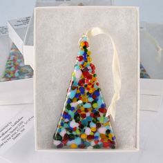 an ornament shaped like a christmas tree in a white box on top of papers