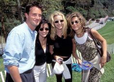 three women and one man posing for a photo in front of a white picket fence