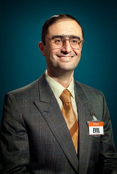 a man in a suit and tie with an evil badge on his lapel pocket