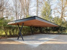 an outdoor covered area with trees and bushes in the backgrouds, surrounded by gravel