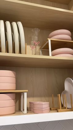 the shelves are filled with dishes and plates in pink, white, and gold colors