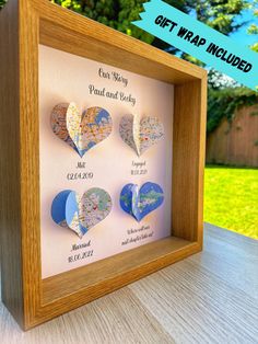 a wooden frame with four heart shaped magnets in the shape of maps on it