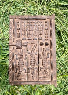 an old wooden carving on the grass with some carvings in it's middle section