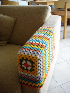 a crocheted blanket sitting on the back of a couch in a living room