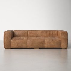 a brown leather couch sitting on top of a white floor