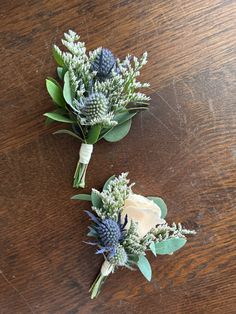 two boutonnieres with flowers on a wooden table