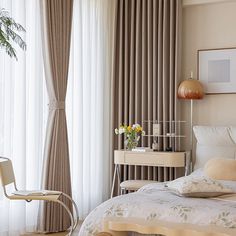 a bedroom with a bed, desk and chair in front of a curtained window