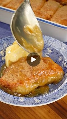 someone is pouring sauce on some food in a blue and white bowl with breaded potatoes