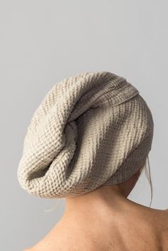 the back of a woman's head wearing a white knitted beanie hat