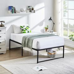 a bedroom with a bed, nightstands and plants on the table in front of it