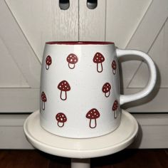 a white and red coffee cup with mushrooms on it