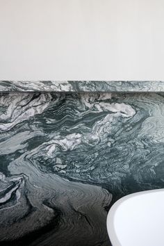 a white sink sitting next to a wall with black and white marble design on it