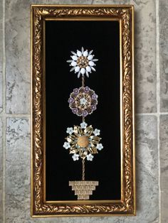 a gold frame with flowers on it hanging on the wall next to a tile floor