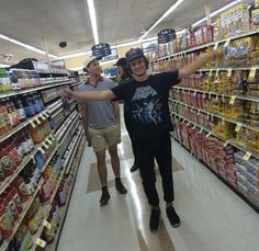 two men are standing in the aisle of a grocery store and one is pointing at something