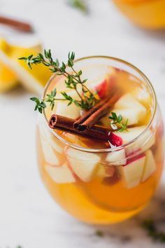 a glass filled with apple cider on top of a table