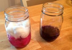 two jars filled with different colored liquids on top of a wooden table