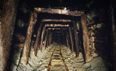 an old train track going through the middle of a tunnel with rocks and wood on both sides