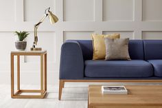 a blue couch sitting next to a wooden table with a lamp on top of it