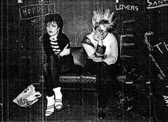 two punk rockers sitting in front of a blackboard