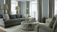 a living room filled with lots of furniture next to two windows and a rug on the floor